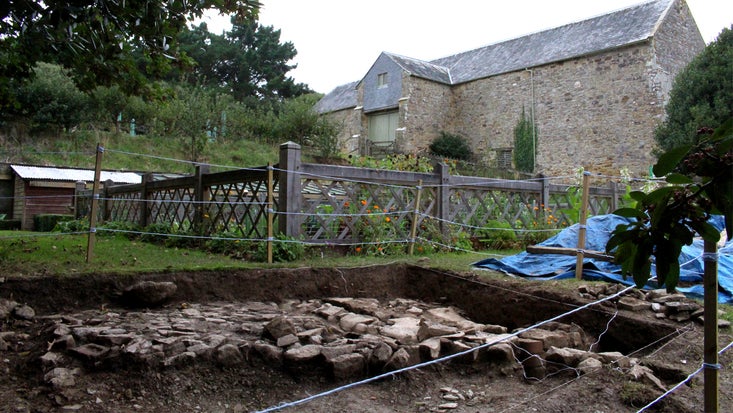 Test pit with a cobbled courtyard exposed from the volunteer-led archaeology dig in Trerice garden, Cornwall